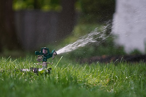sprinkler watering healthy grass to represent lawn care services in Hudson, Wisconsin.