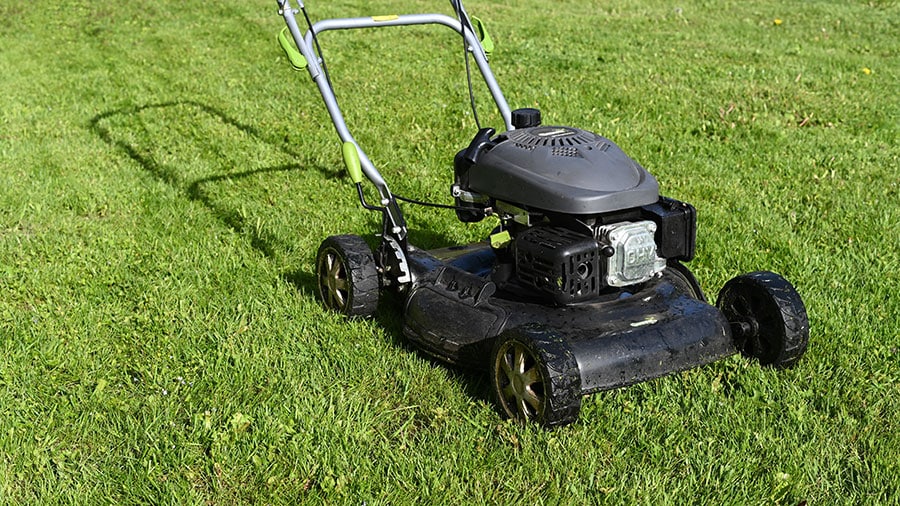 Lawnmower mowing healthy grass to represent lawn care services in Savage, Minnesota